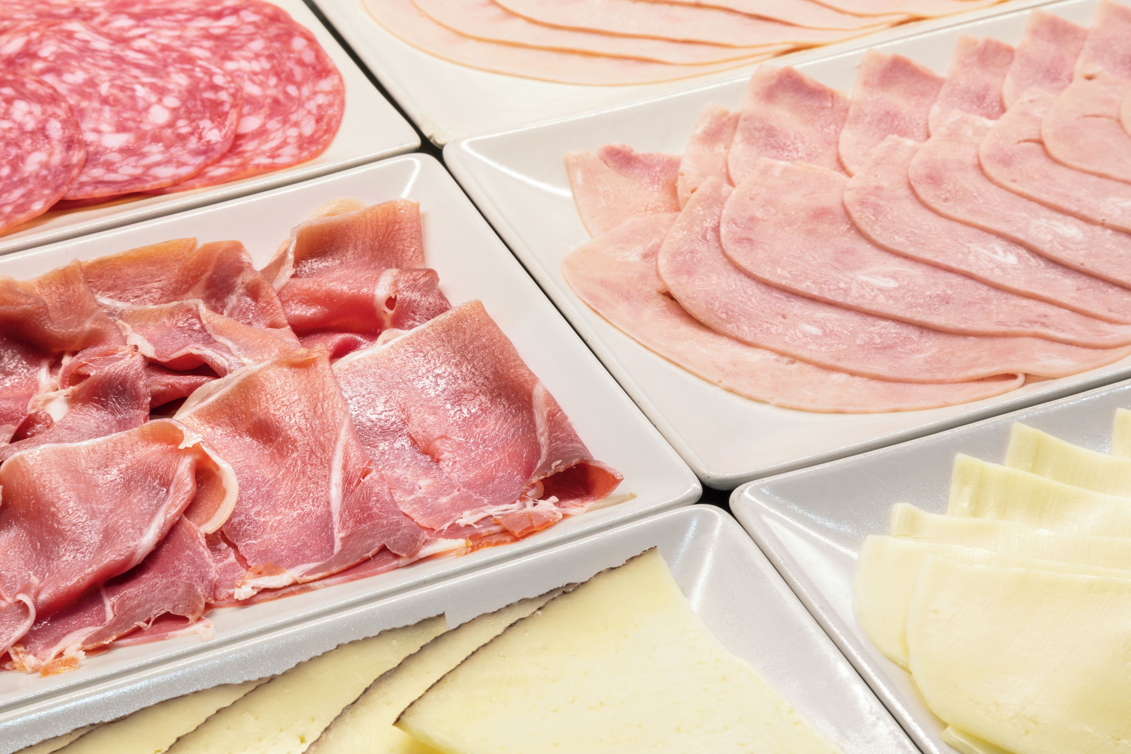 Tagli di salumi e formaggi su vassoi.