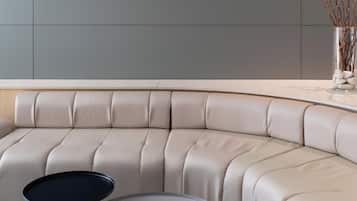 Un sofá moderno de líneas curvas con respaldo y reposabrazos acolchados, ubicado en una habitación contemporánea con una paleta de colores neutros.