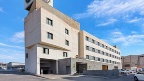 A B&B hotel with a modern design, featuring a prominent sign, multiple windows, and a parking area.