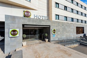 A B&B hotel entrance with a modern facade, glass doors, and a small potted plant. - B&B Hotel Elche (Elche)