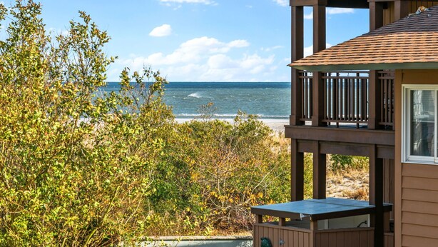 A wooden deck overlooking a beach with a view of the ocean.