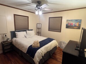 A bedroom with a bed, a ceiling fan, a wall-mounted TV, and a painting. - Riverfront, Hot tub, shared pool, minutes to slopes with large covered deck! (Banner Elk)