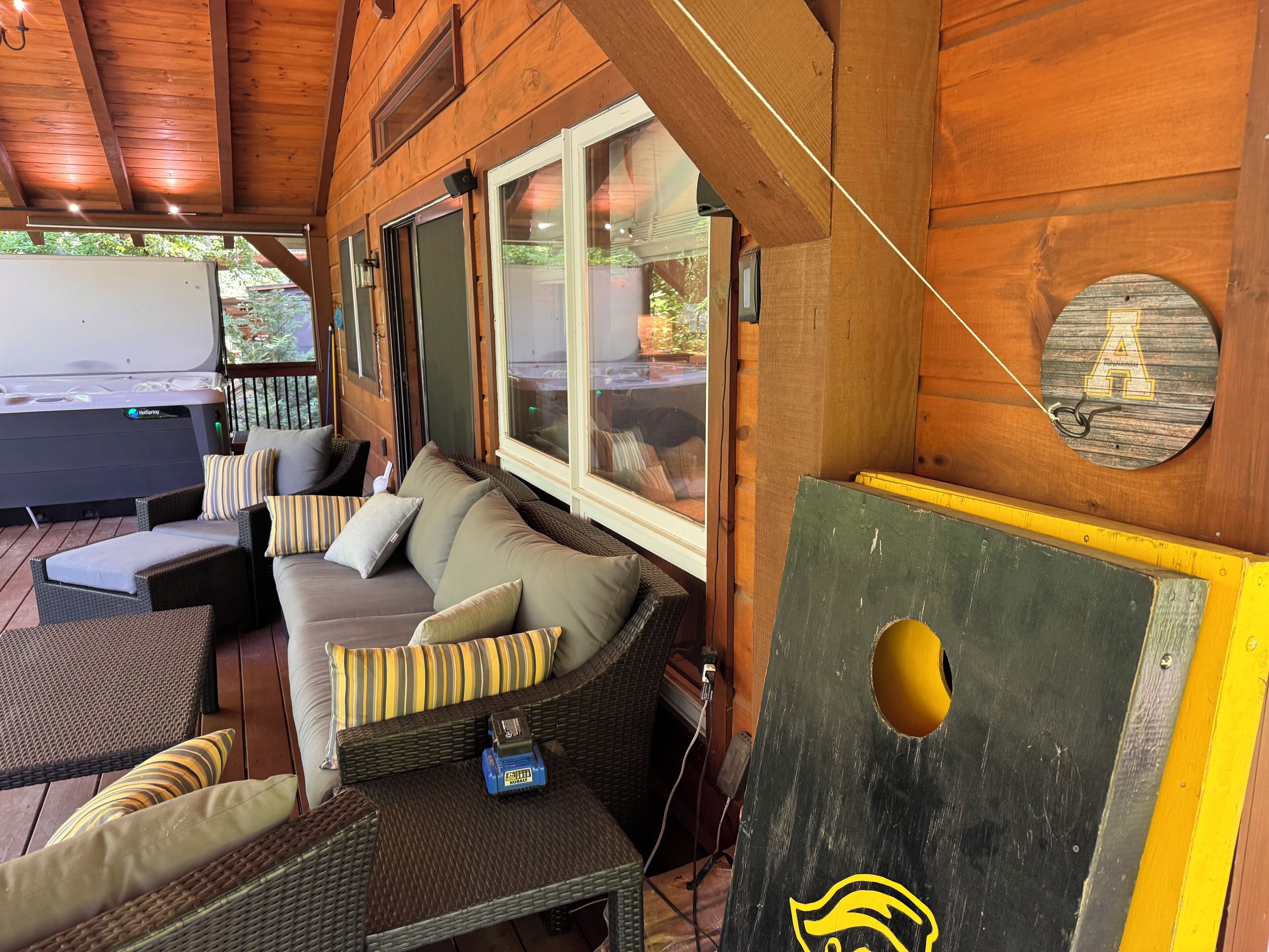 A wooden interior with a sofa, cushions, and a hot tub.