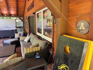 A wooden interior with a sofa, cushions, and a hot tub.