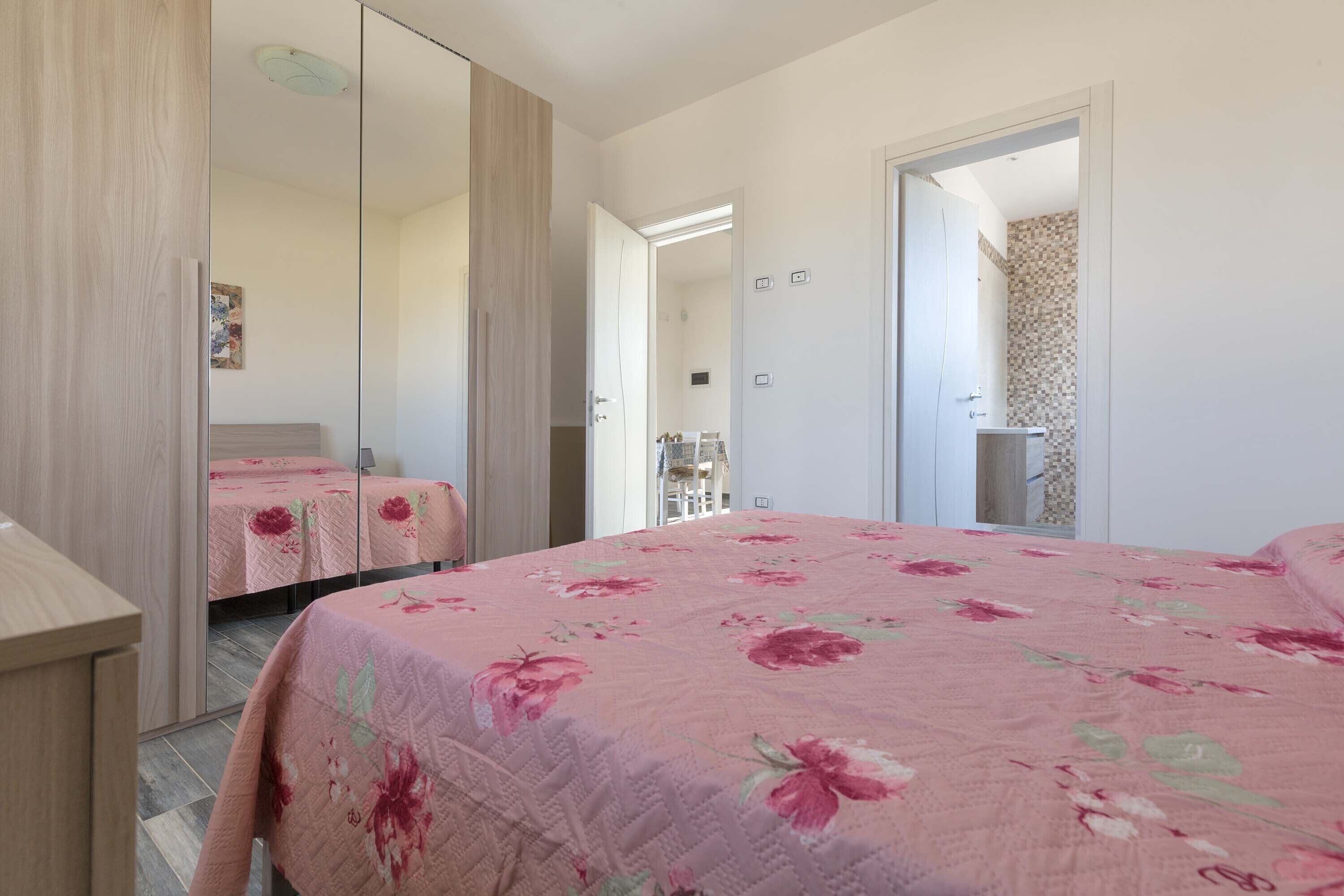 Un dormitorio con una cama grande, un armario y un espejo.