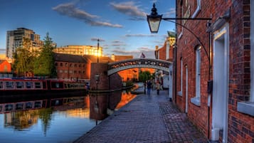 A canal with a pedestrian bridge, brick buildings, and a red boat.
