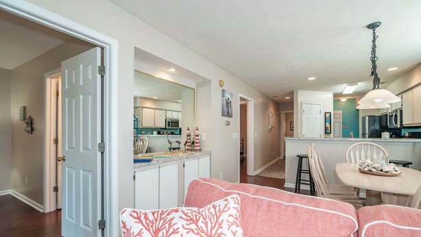 A modern kitchen with white cabinets, a central island, and a dining area with a white table and chairs. - TB 12A First Floor 3BR/3BA with great view of golf course w/no stairs (PAWLEYS ISLAND)