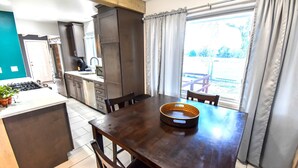 Een moderne keuken met donkere houten kasten, een inbouwfornuis en een eethoek met een donkere houten tafel en stoelen.