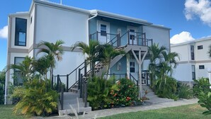 Un bâtiment moderne à deux étages, doté d’un escalier central et entouré de plantes et de fleurs tropicales.