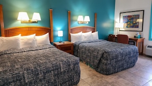 Een hotelkamer met twee bedden, nachtkastjes, een bureau en een stoel.