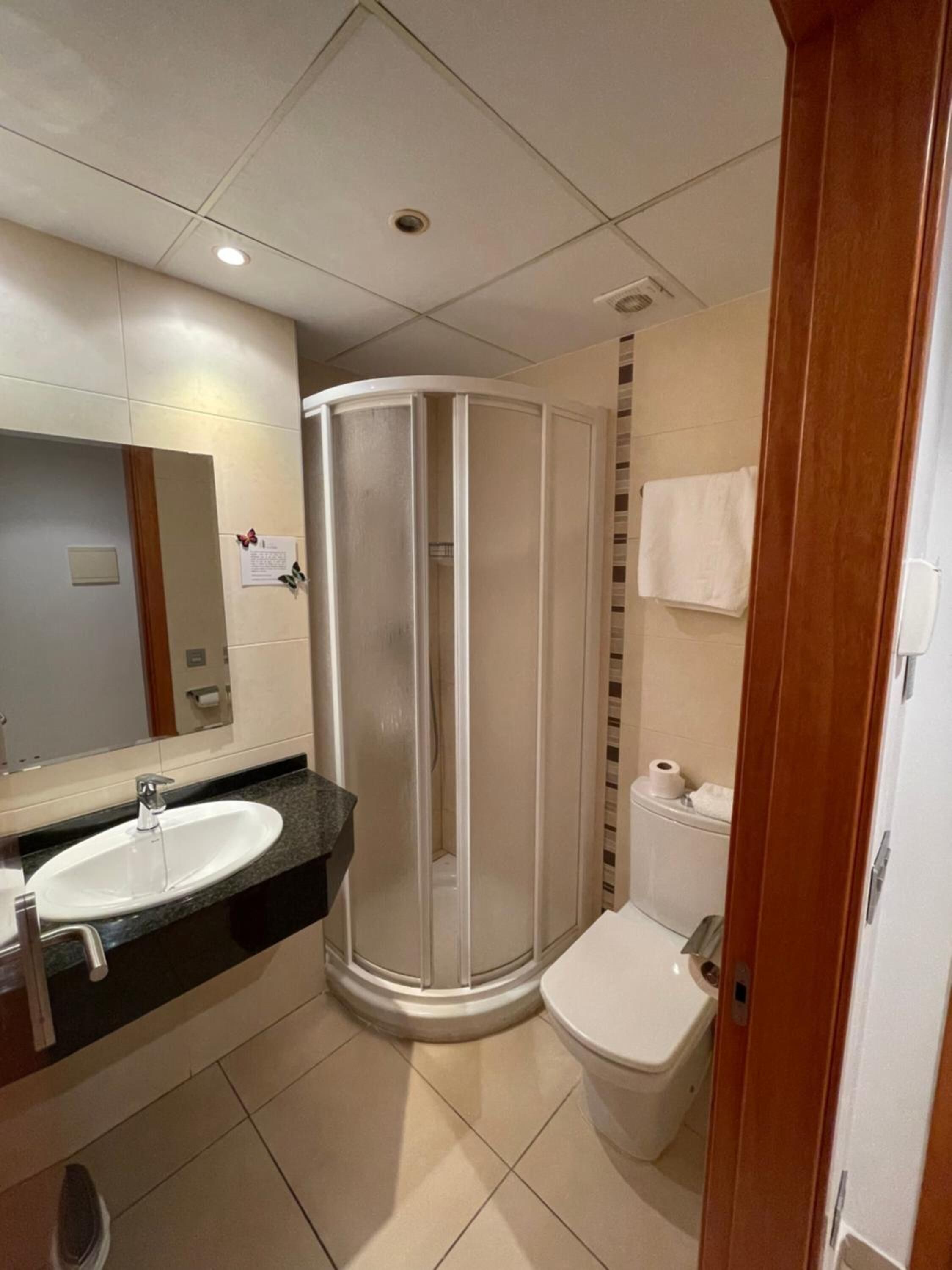 Un baño con lavamanos, espejo, inodoro y cabina de ducha.