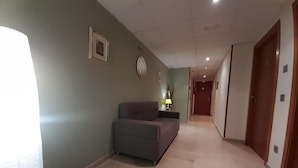 Ein Flur mit einer Couch, einer Lampe und einer Tür am Ende.