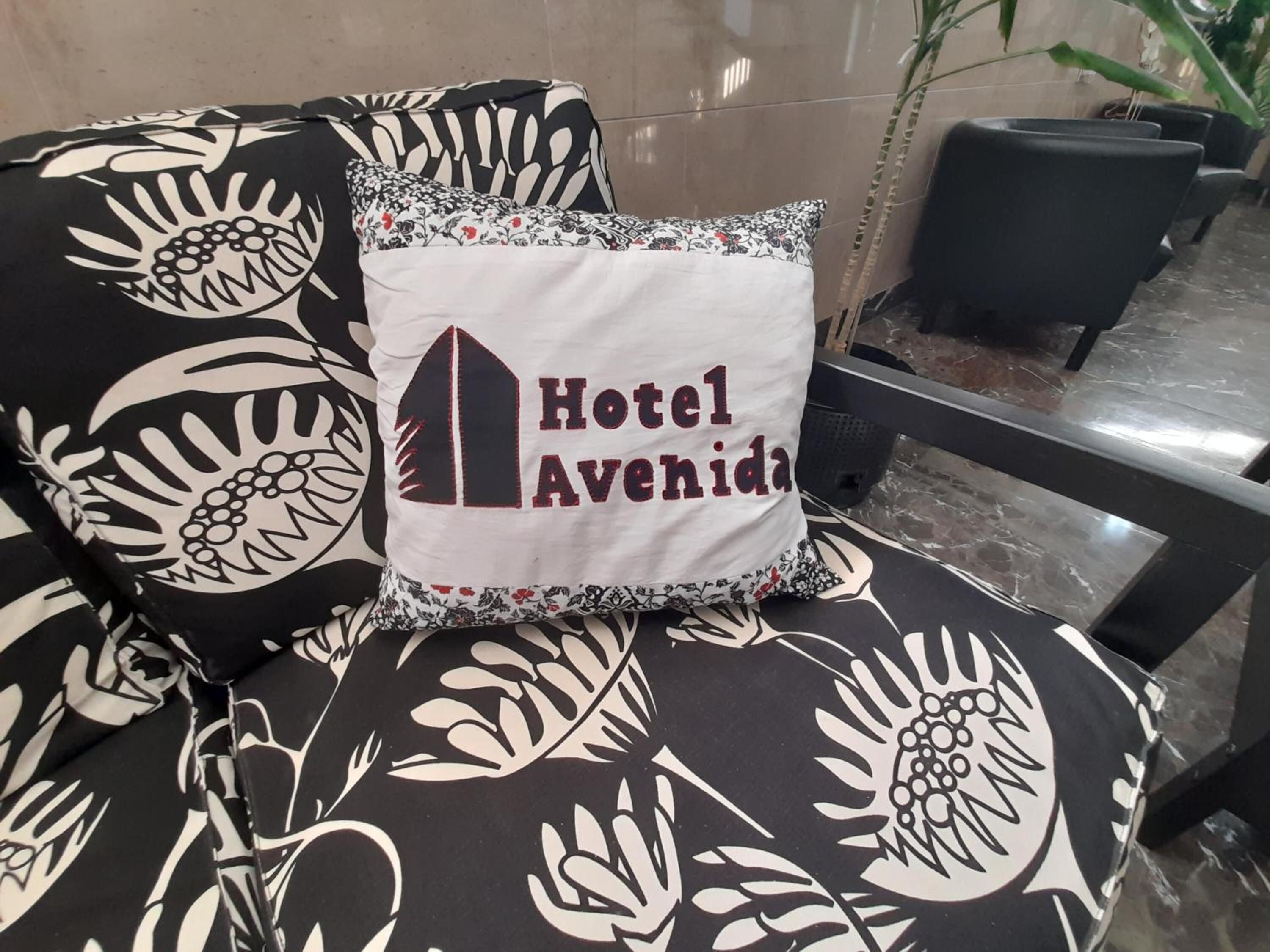 Een stoel met een bloemenmotief en een kussen met de tekst 'Hotel Avenida'.