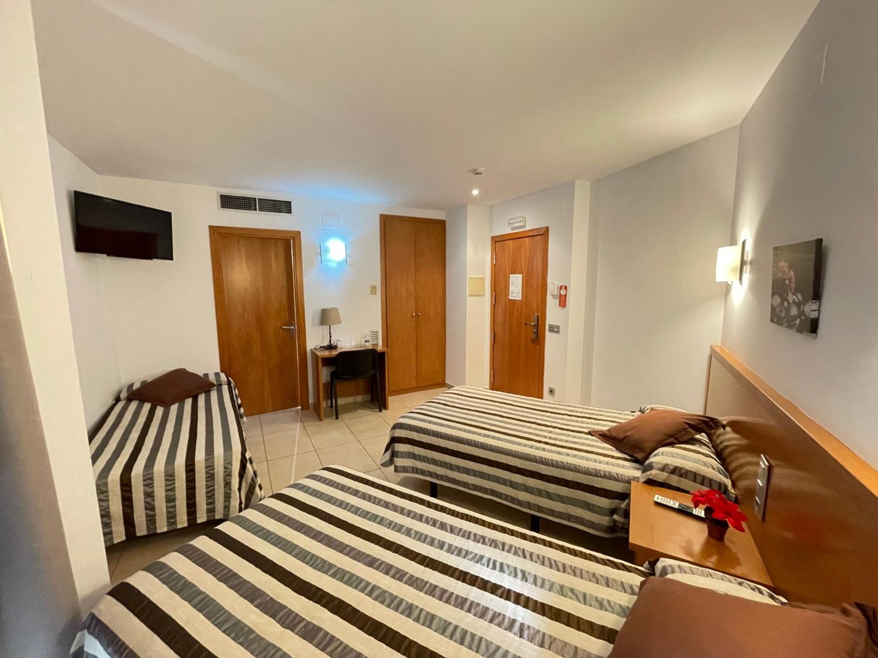 Una habitación de hotel con dos camas, un escritorio, una silla y un televisor.