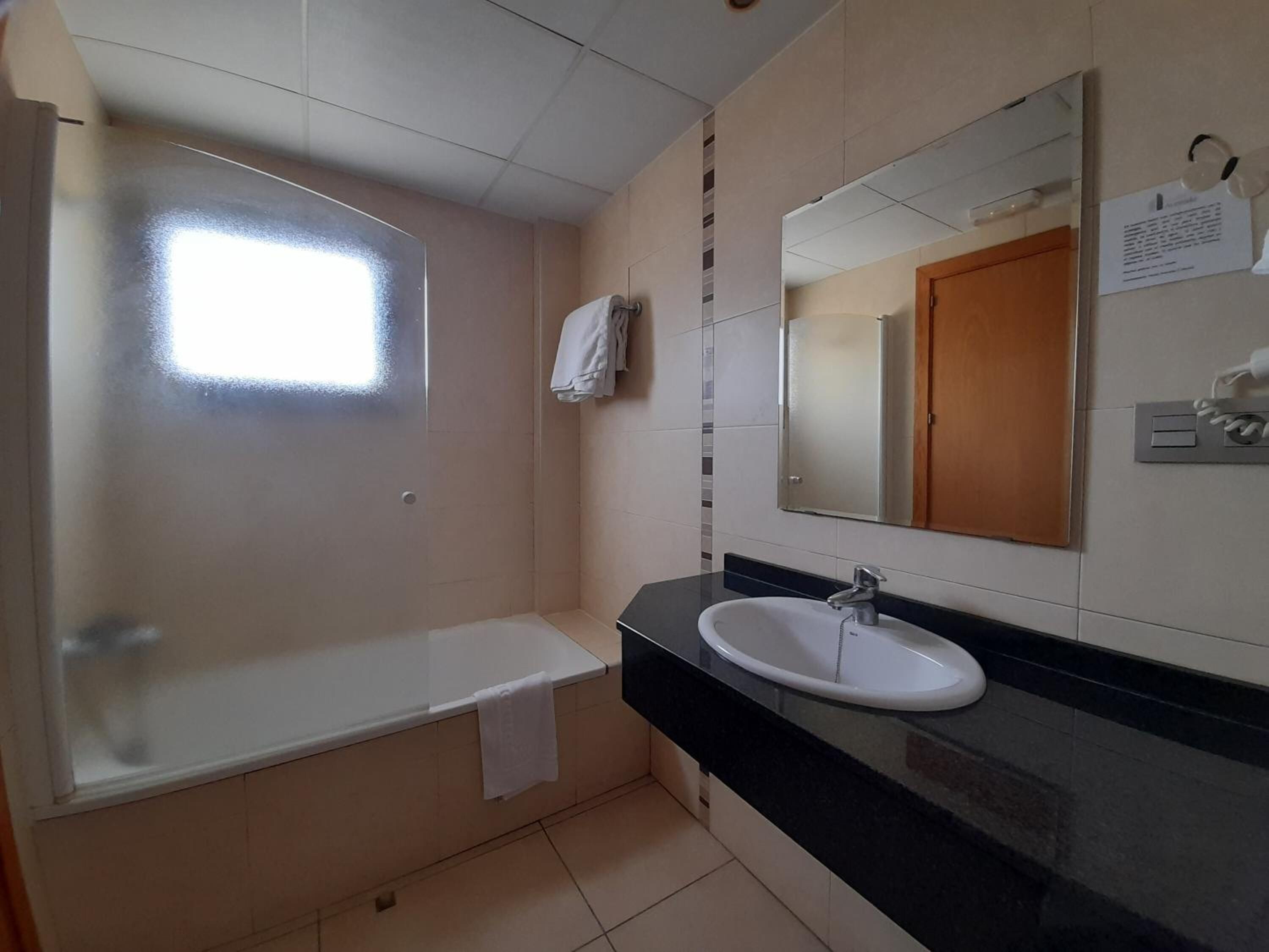 Un baño con bañera, lavamanos y espejo.