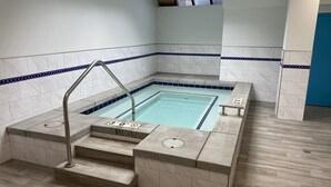 Une piscine avec des marches permettant d’y accéder, entourée de murs recouverts de carreaux blancs et bleus.
