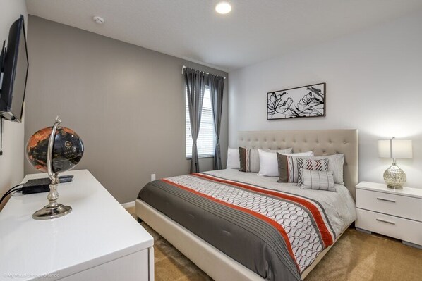 A bedroom with a bed, bedside tables, a desk, and a globe.