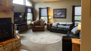 Ein Wohnzimmer mit Kamin, Fernseher, Sofa und Couchtisch.
