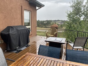A covered patio with a grill, a table, and two chairs. - Serene Retreat Nestled in the pines- private & relaxing; Microweddings; Reunions (Colorado Springs)