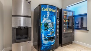 A vending machine with a 'Cold Drinks' sign, a water dispenser, and a snack vending machine in a room with a window. - Red Roof Inn La Porte (La Porte)