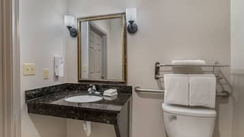A bathroom with a marble sink, a white toilet, a towel rack, and a mirror with a gold frame.