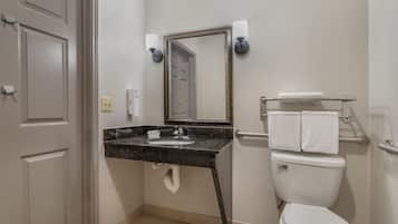 Een badkamer met een wastafel, spiegel, toilet en handdoekhouder.