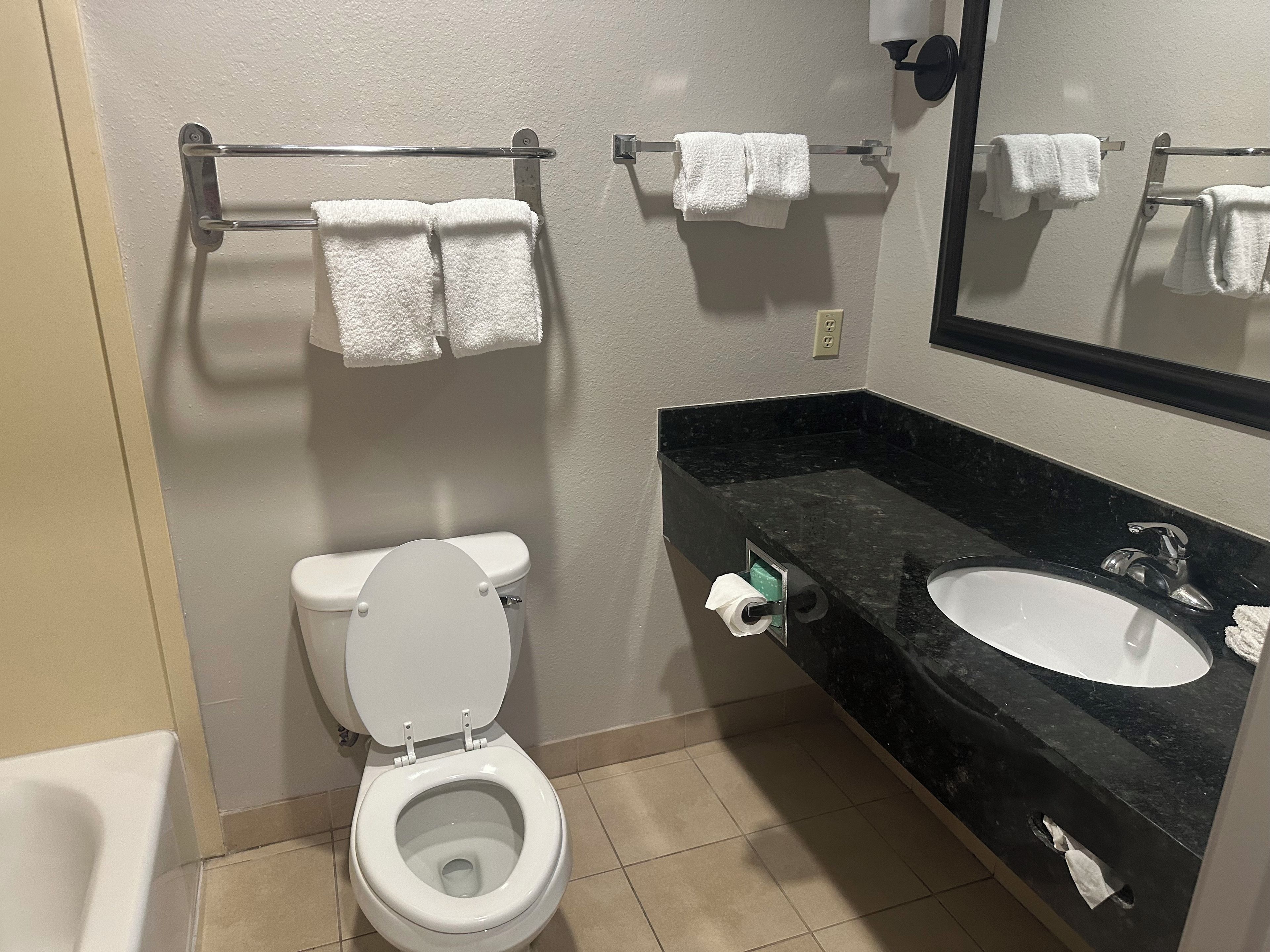 A bathroom with a toilet, a sink, and a towel rack with multiple towels.