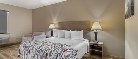 A hotel room with a large bed, two bedside lamps, a chair, a desk, and a window.