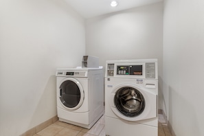 A laundry room with two front-loading washing machines and a dryer.