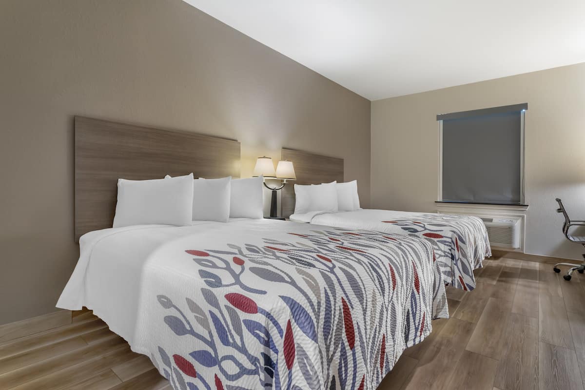Quarto de hotel com uma cama grande, uma mesa de cabeceira com luminária, uma janela e vista para o exterior.