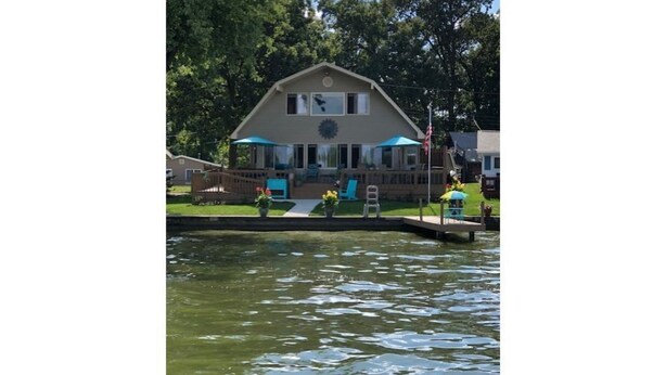 Une maison avec un porche, une petite terrasse et un élément décoratif aquatique à l’avant.