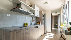 Une cuisine moderne avec des meubles de couleur bois clair, une hotte en acier inoxydable et un four encastré.