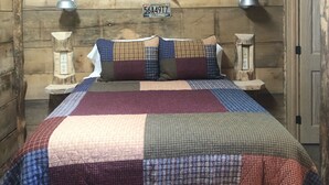 Una habitación rústica de madera con una cama, dos lámparas de pared y una escalera.