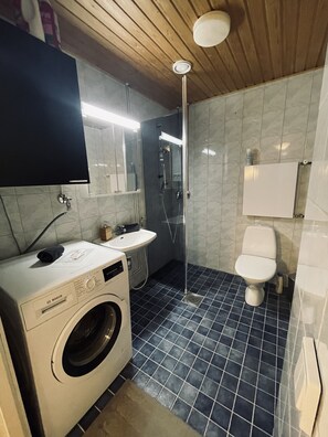 A compact bathroom with a washing machine, sink, and toilet. - STAY Sello Business Suite (Espoo)