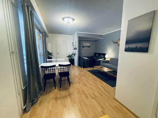 Ein kompakter Wohnbereich mit Essplatz, einer Couch und einem Bett.