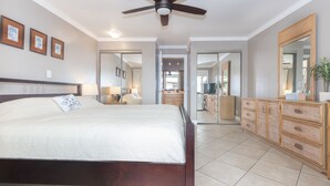 A bedroom with a large bed, wooden dresser, and a ceiling fan.