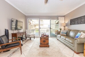 Relax in style with a comfortable sofa, flat-screen TV, and sliding glass door leading to a balcony.