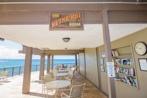 Enjoy ocean views from this outdoor dining and social space, featuring comfortable seating and a library area.