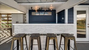 Eine moderne Küche mit dunkler Spritzschutzwand, weißer Arbeitsplatte und drei Barhocker.