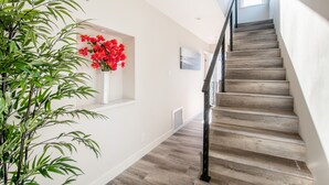 A staircase with wooden steps and a black railing, leading to an upper floor.