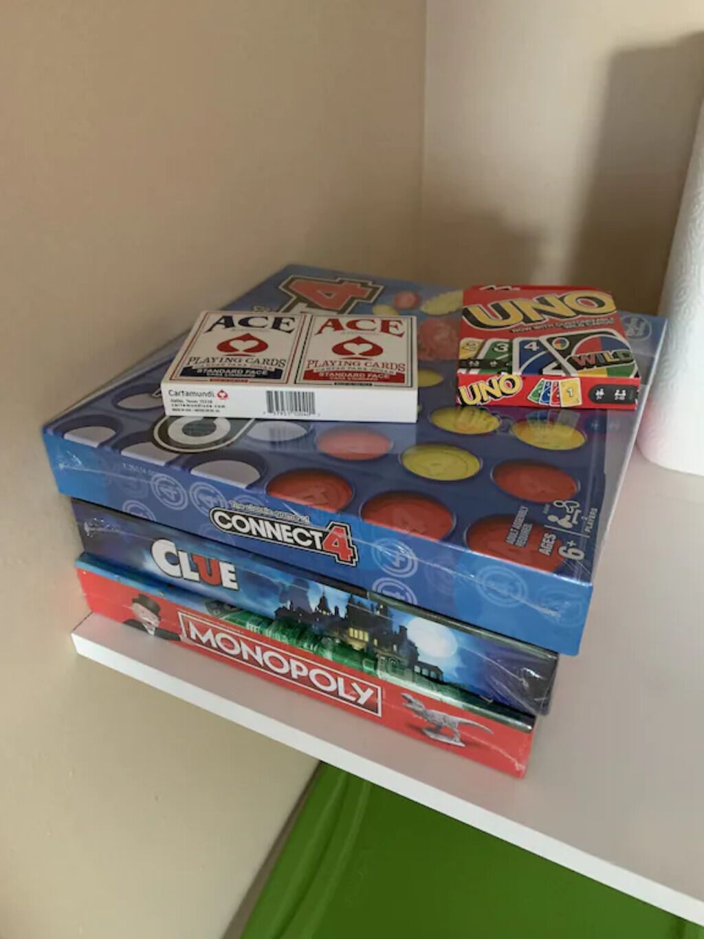 Une pile de jeux de société, dont UNO, Connect 4, Cluedo et Monopoly, est posée sur une étagère.