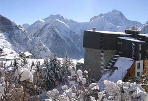 Ein Hotel mit modernem Design, gelegen in einer verschneiten Bergregion mit freiem Blick auf die umliegenden Gipfel.