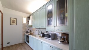 A kitchen with light blue cabinets, a microwave, a sink, and a window above the counter.