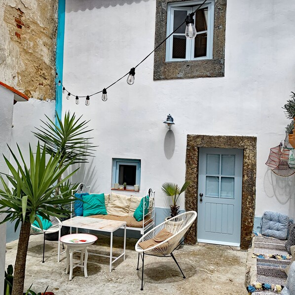 Relax in this serene outdoor seating area with a table, chairs, and sofa, surrounded by lush greenery and a beautiful view.