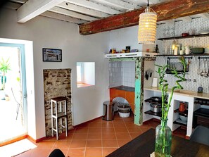 Una cocina con pared de ladrillo rústico, lámpara colgante y suelo de baldosas.