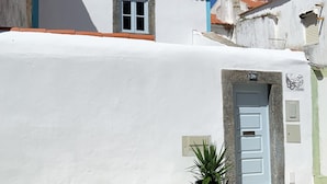 A white building with a red-tiled roof, a small window, and a door with a number plate. - Casa Pescador Peniche (Peniche)