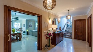 Un pasillo amplio con comedor, una escalera y un jarrón decorativo con flores.