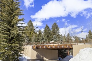 A wooden bridge over a road with snow on the sides, surrounded by trees and a clear sky. - Outpost: Moose Creek 34 - Private Hot Tub! (Teton Village)