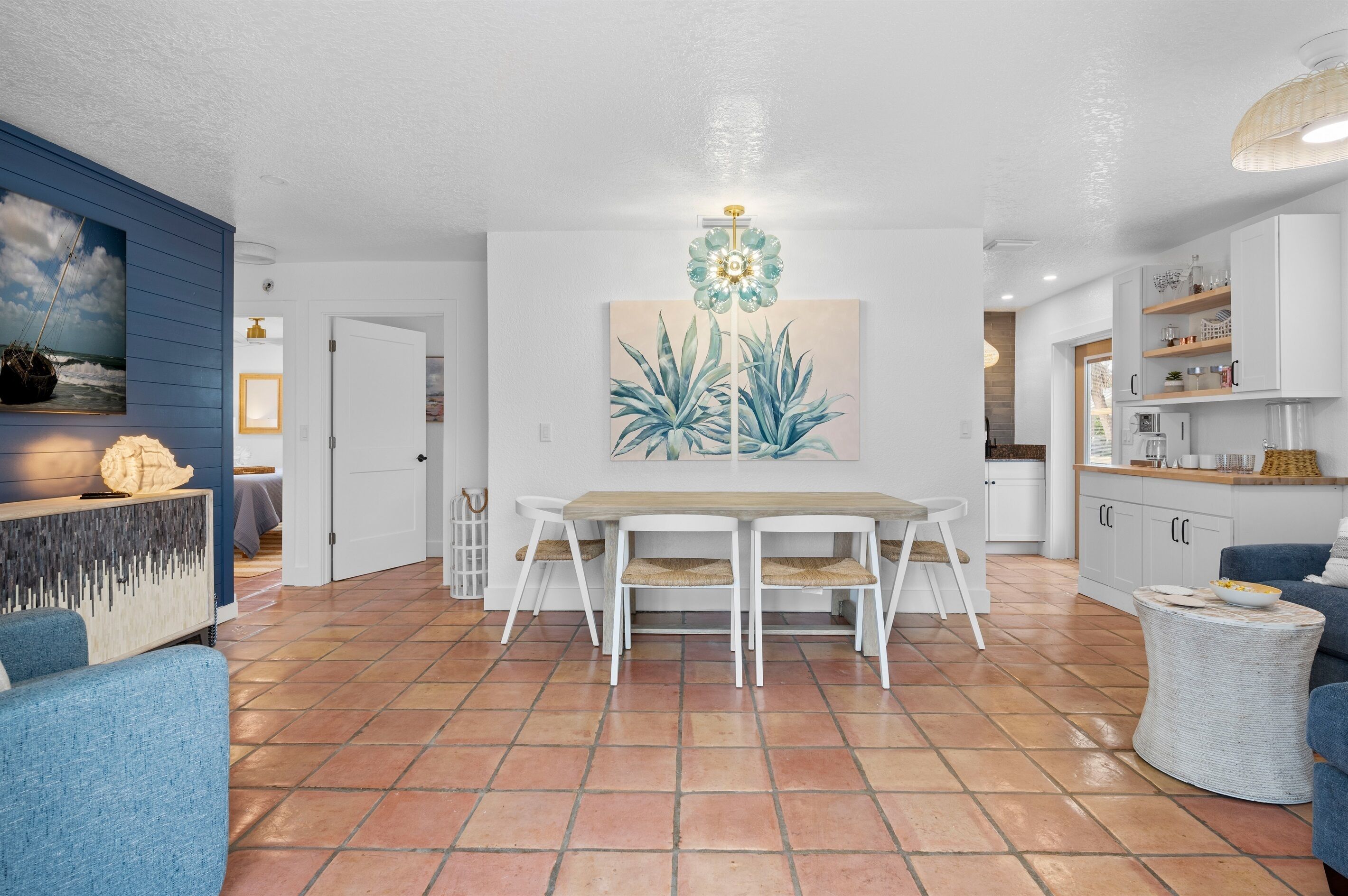 A spacious living area with a dining table, chairs, and a kitchen in the background.