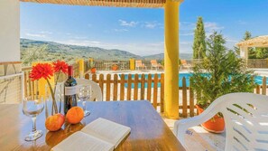 A table with a book, wine glasses, and fruit, overlooking a pool and mountains. - Casas de Paquita - El Establo Montefrío by Ruralidays (Granada)